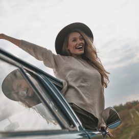 Beautiful day. Attractive young smiling woman leaning out the van?s window and keeping arms outstretched while enjoying the car travel